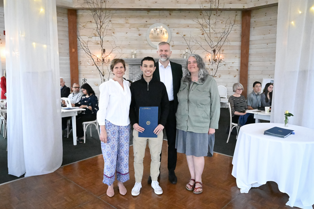 An RCS senior holds a plaque while he is surrounded by two teachers and the district superintendent during an award ceremony honor both student and teachers for volunteer work.